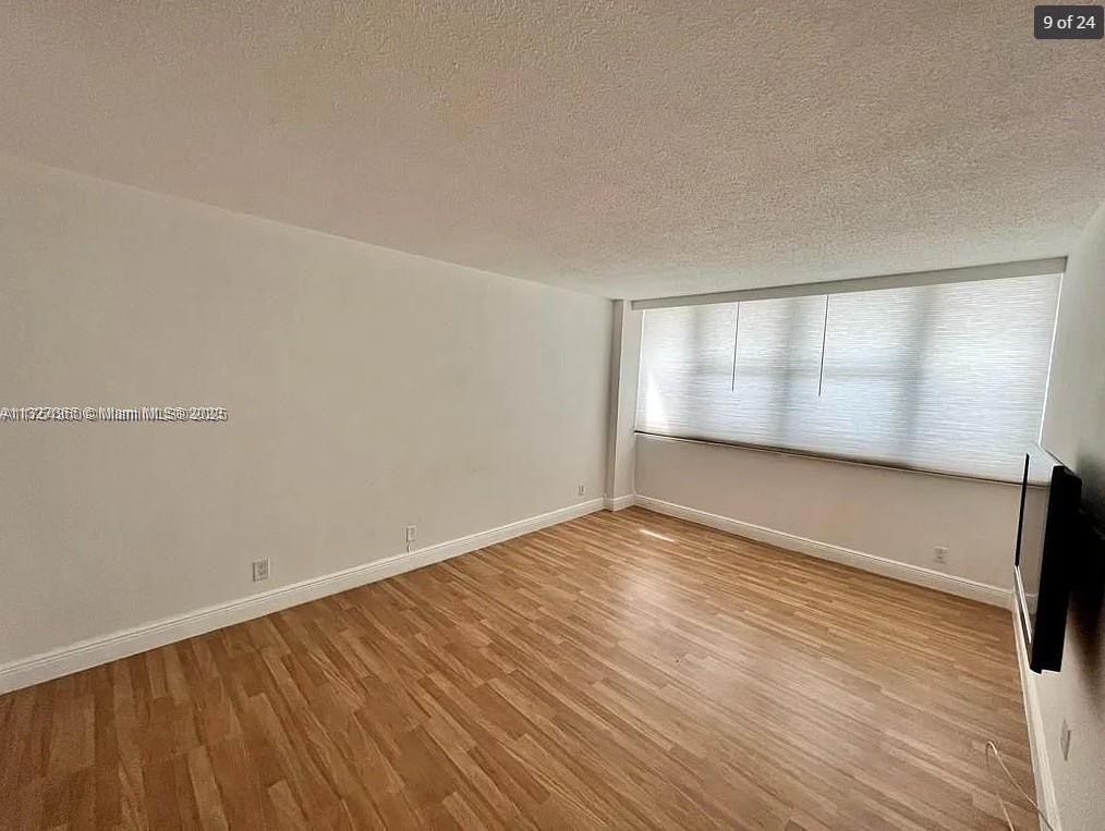 An empty room features light wood-look flooring, white walls, and a large window with blinds — 2030 S Ocean Dr # 211, Hallandale Beach FL 33009, HALLANDALE BEACH, FL