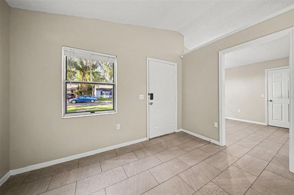 An entryway with beige walls, tile flooring, a white front door, and a window — 2710 LORRAINE DRIVE, LEESBURG, FL