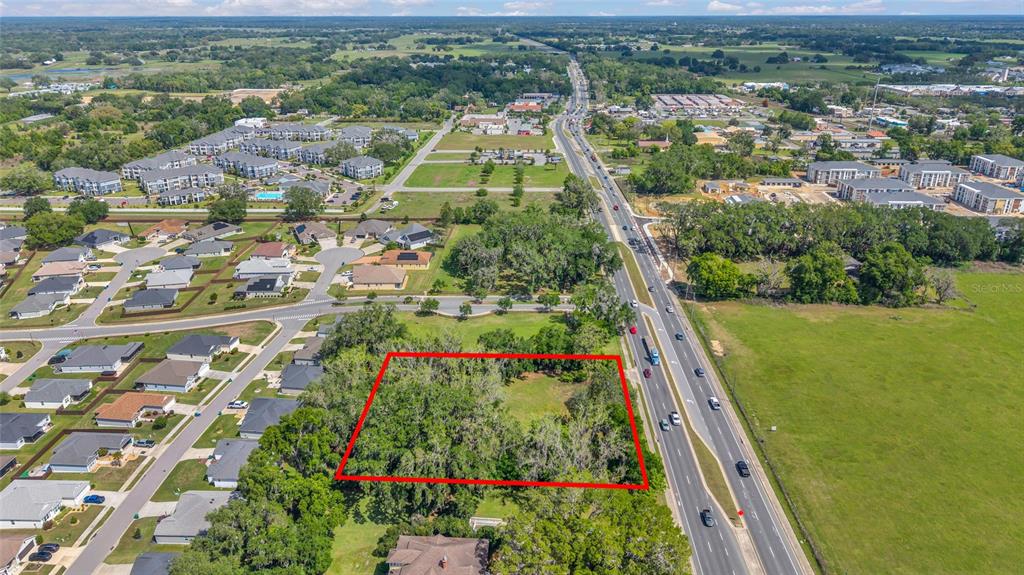 An aerial view shows a rectangular, tree-covered vacant lot outlined in red next to a highway — 11338 N US HIGHWAY 301, OXFORD, FL