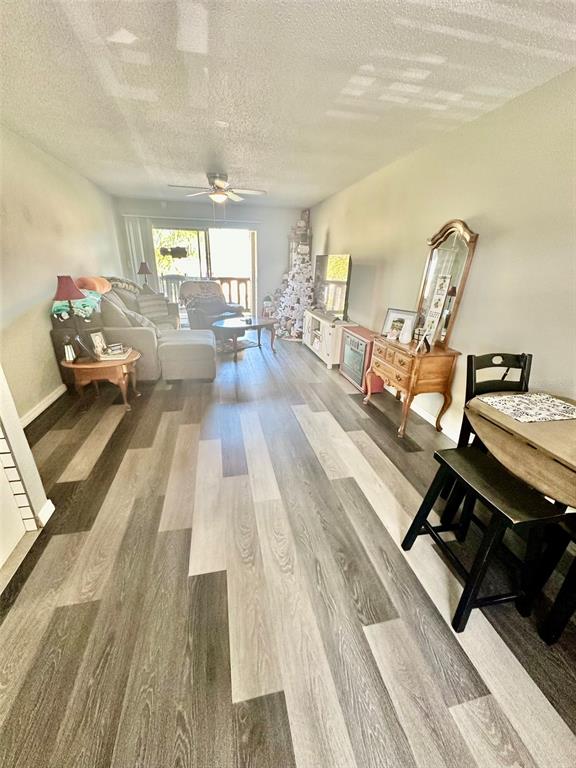 A living room features wood-look plank flooring, a ceiling fan, and a sliding glass door — 5207 TURQUOISE LANE UNIT 202, NEW PORT RICHEY, FL