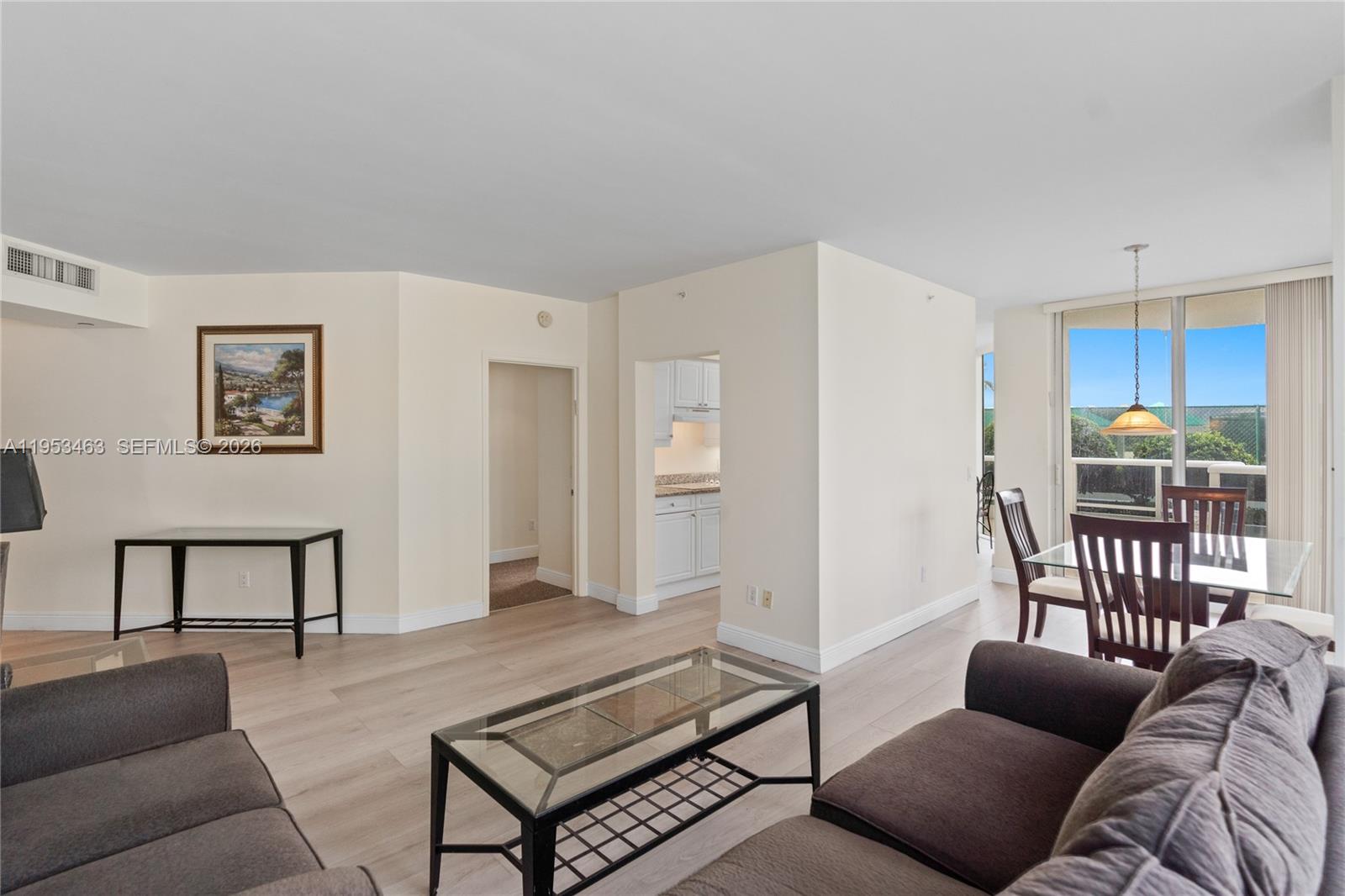 A living and dining area features light wood flooring, neutral walls, and a glass-topped coffee table — 4775 Collins Ave # 507, Miami Beach FL 33140, MIAMI BEACH, FL
