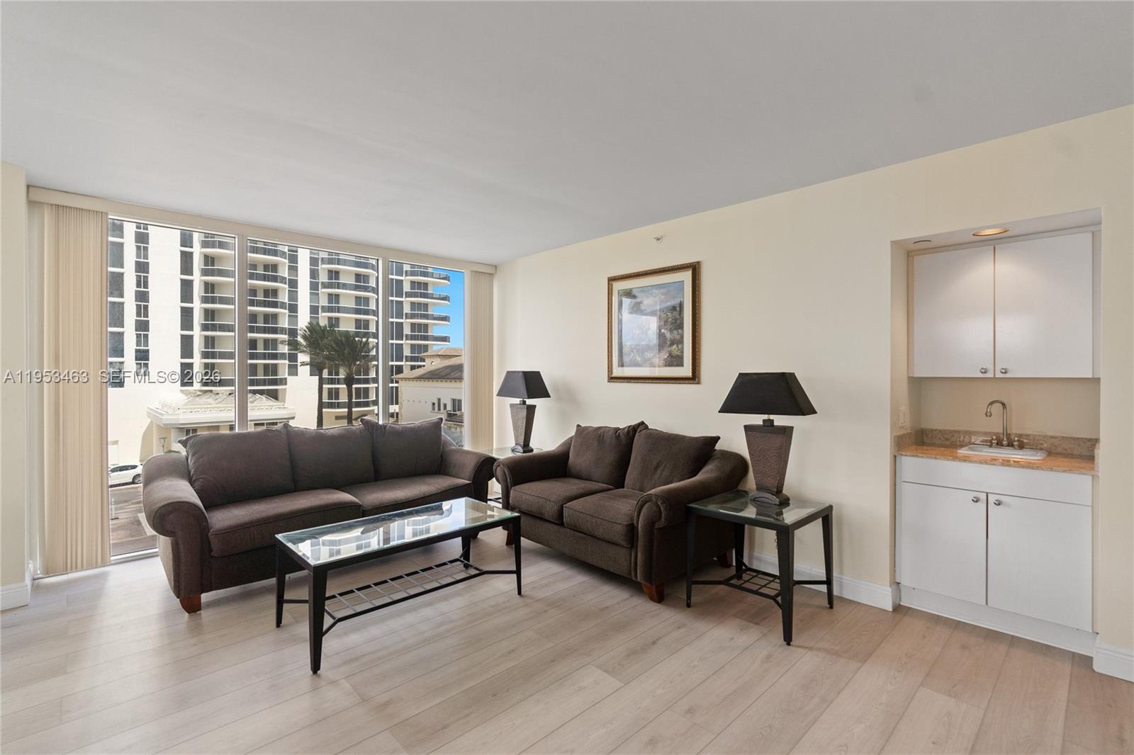 A living room features two brown sofas, a glass coffee table, and a wet bar — 4775 Collins Ave # 507, Miami Beach FL 33140, MIAMI BEACH, FL