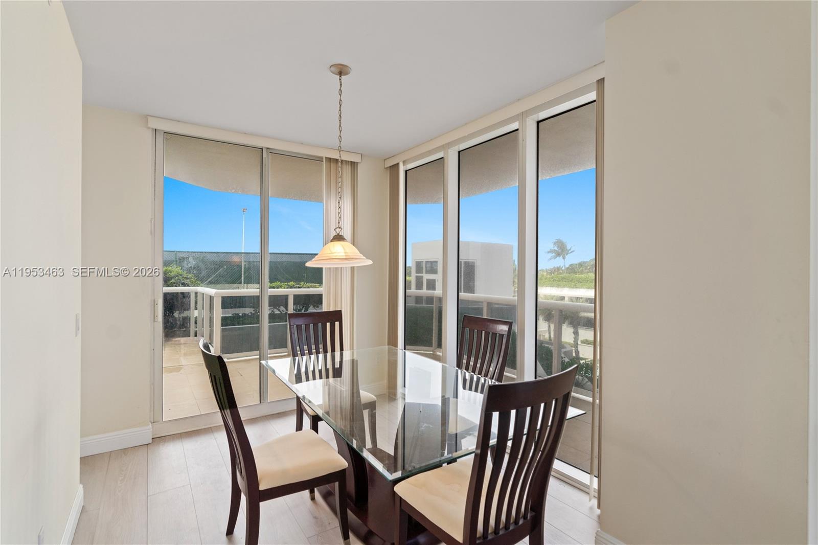 A dining area features a glass-topped table, four wooden chairs, and floor-to-ceiling windows — 4775 Collins Ave # 507, Miami Beach FL 33140, MIAMI BEACH, FL