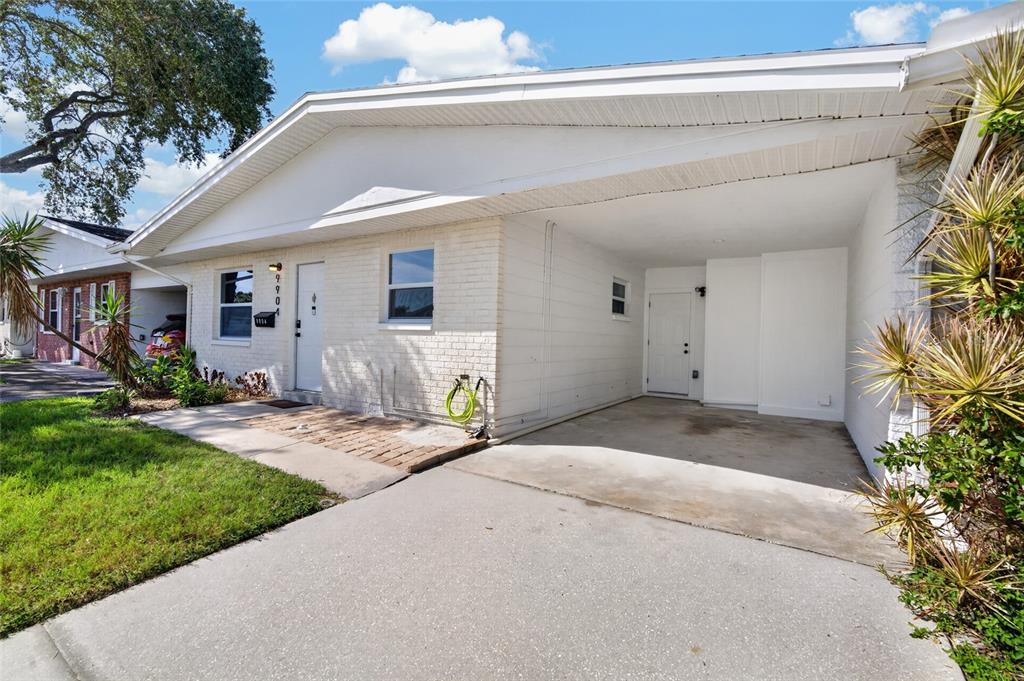 A white brick house features a covered carport and a small front patio area — 9904 TULIP STREET N, PINELLAS PARK, FL