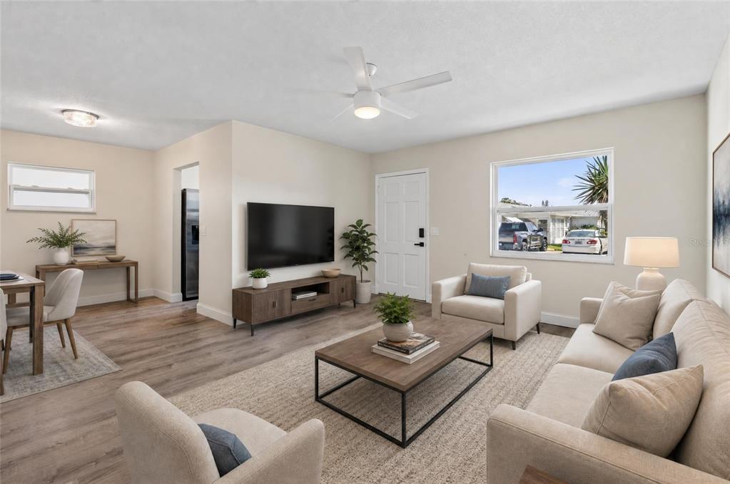 A bright living room features light wood-look flooring, a white ceiling fan, and neutral furniture — 9904 TULIP STREET N, PINELLAS PARK, FL