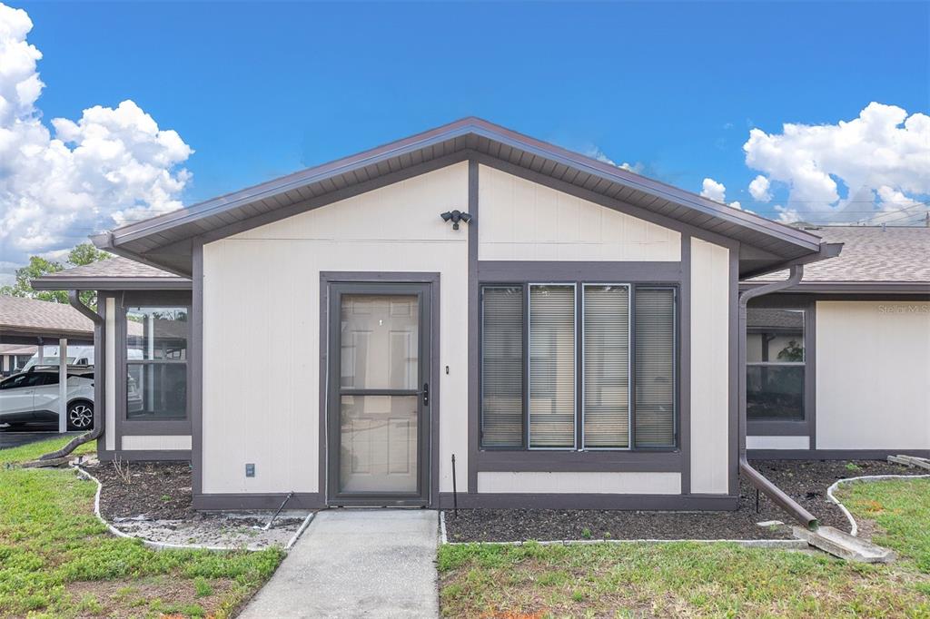 The exterior of a single-story house features light siding, dark trim, and a front walkway — 37730 ALISSA DRIVE, ZEPHYRHILLS, FL