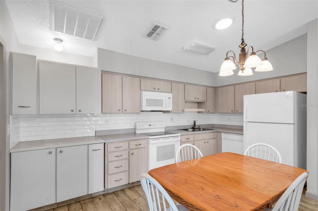 A kitchen features light wood cabinets, white appliances, a white subway tile backsplash, and wood flooring — 37730 ALISSA DRIVE, ZEPHYRHILLS, FL