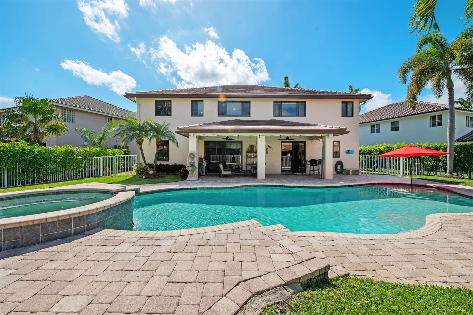 A two-story house with a backyard pool, spa, and covered patio under a blue sky — 978 Greenwood Road, Weston FL 33327, WESTON, FL
