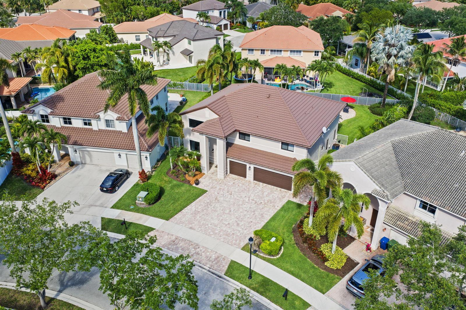 An aerial view shows suburban houses with brown tiled roofs, palm trees, and paved driveways — 978 Greenwood Road, Weston FL 33327, WESTON, FL