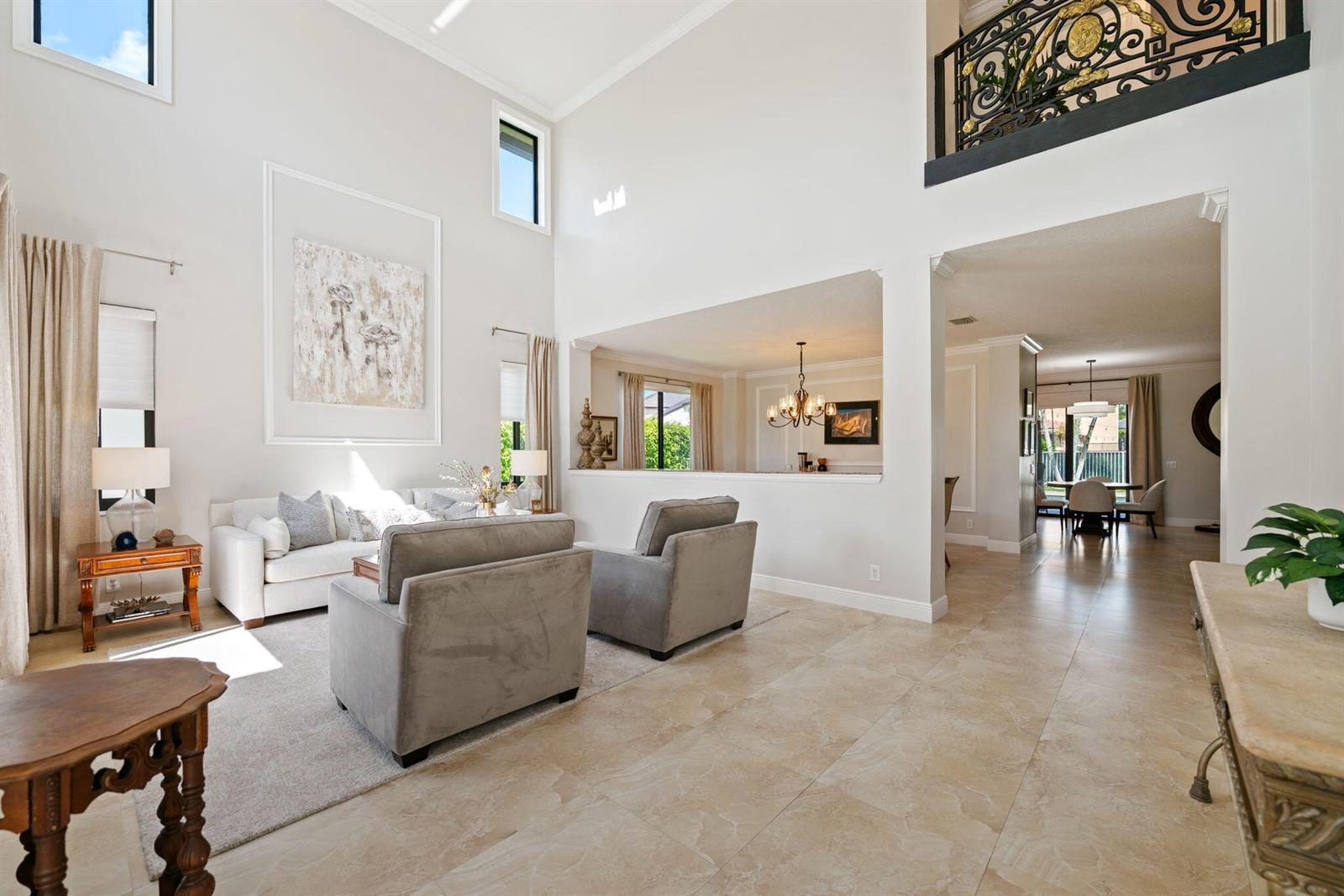 A high-ceilinged living room features tile floors, neutral furniture, and an open view to a dining area — 978 Greenwood Road, Weston FL 33327, WESTON, FL