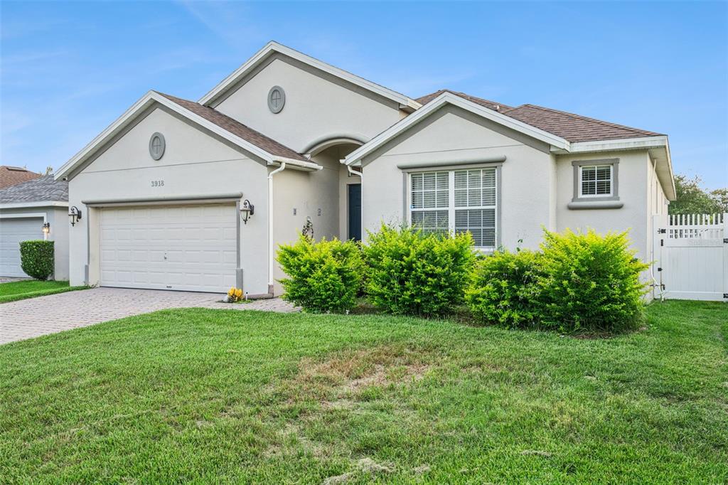 A single-story house with a beige stucco exterior, a two-car garage, and a front lawn — 3918 WATERSEND DRIVE, ORLANDO, FL
