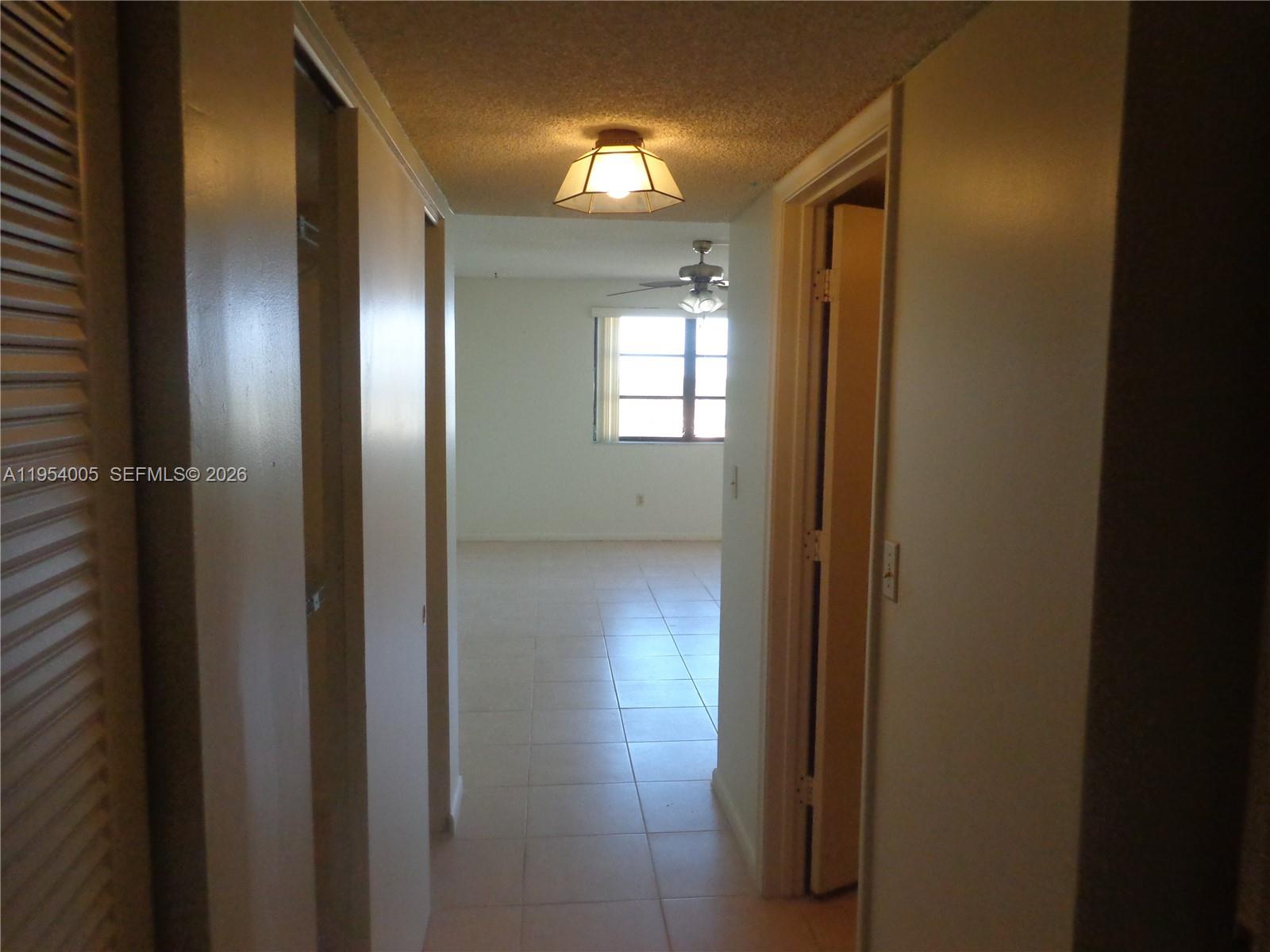 A hallway with tile flooring leads to a room with a window and ceiling fan — 20850 San Simeon Way # 5, Miami FL 33179, MIAMI, FL