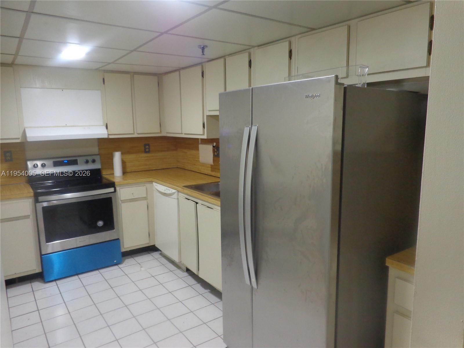 A kitchen features white cabinets, a stainless steel refrigerator, a black stove, and tiled floors — 20850 San Simeon Way # 5, Miami FL 33179, MIAMI, FL