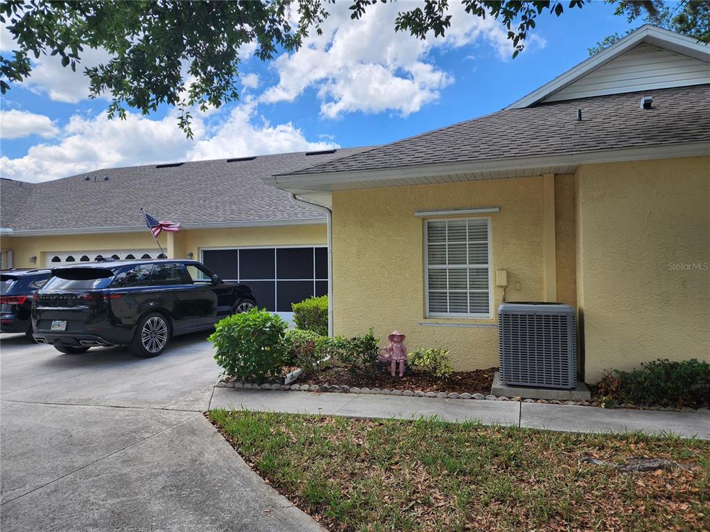 A yellow house exterior features a garage, a driveway with a car, and landscaping — 1542 RED OAK LANE, PORT CHARLOTTE, FL