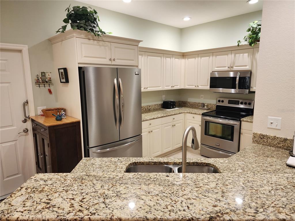 A kitchen features cream cabinets, stainless steel appliances, and granite countertops — 1542 RED OAK LANE, PORT CHARLOTTE, FL
