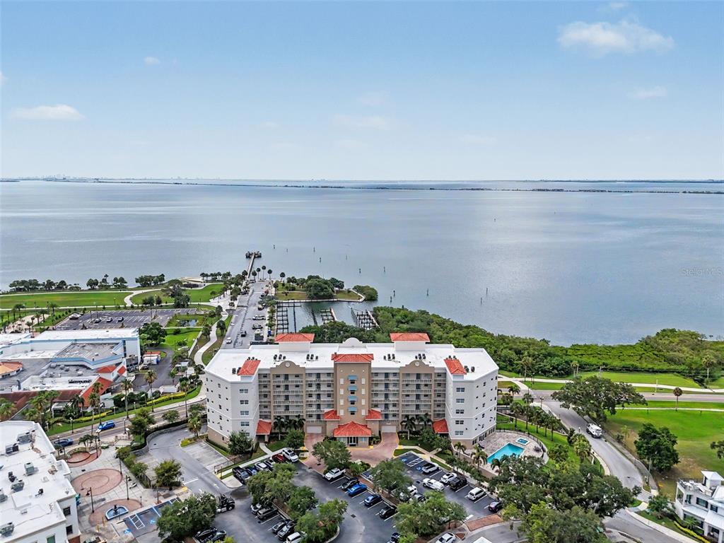 An aerial view shows a multi-story apartment building situated near a large body of water — 101 S BAYSHORE BOULEVARD UNIT 49, SAFETY HARBOR, FL