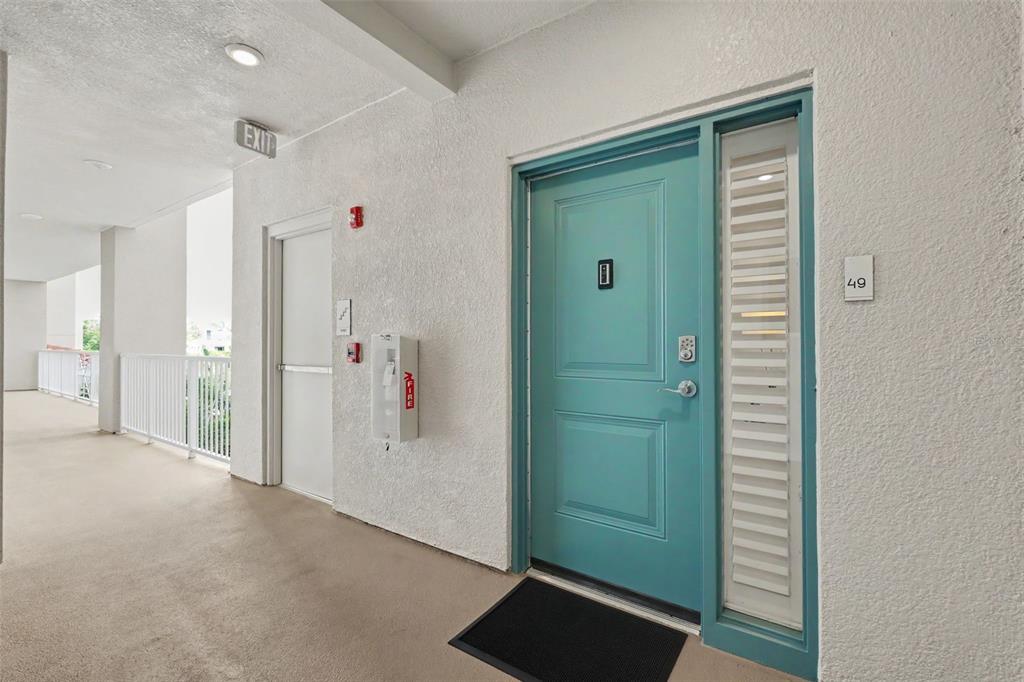 A teal front door with a side window and unit number 49 in a hallway — 101 S BAYSHORE BOULEVARD UNIT 49, SAFETY HARBOR, FL