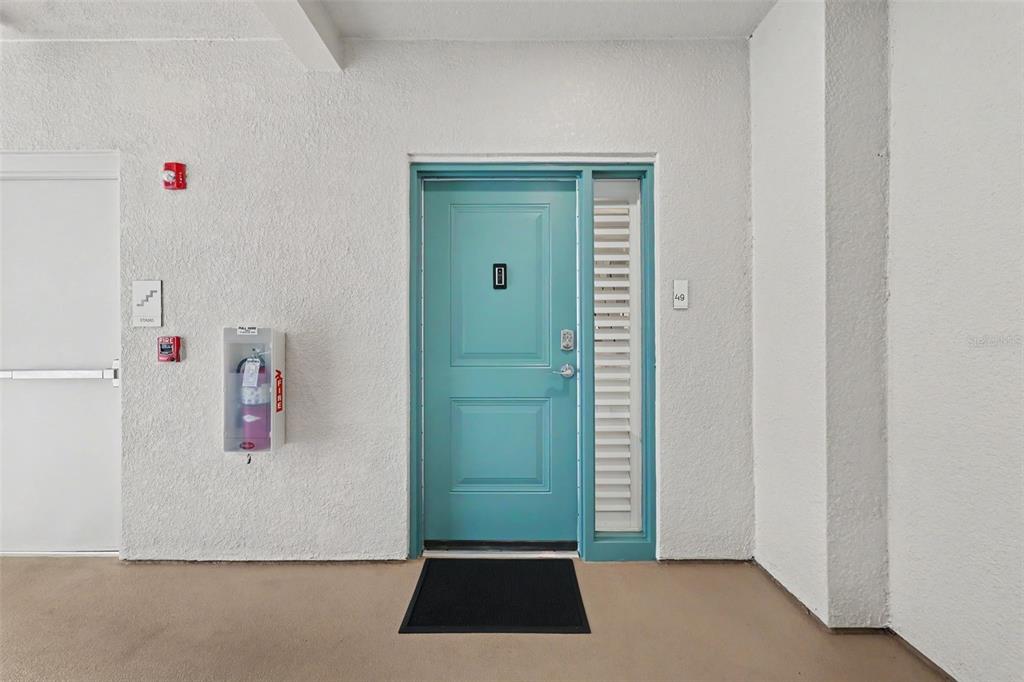 A teal front door with a side window and a fire extinguisher on a balcony — 101 S BAYSHORE BOULEVARD UNIT 49, SAFETY HARBOR, FL