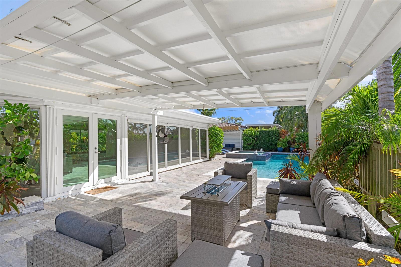 A covered patio features gray wicker furniture, a fire pit table, and a swimming pool — 391 SE 7th Avenue, Pompano Beach FL 33060, POMPANO BEACH, FL