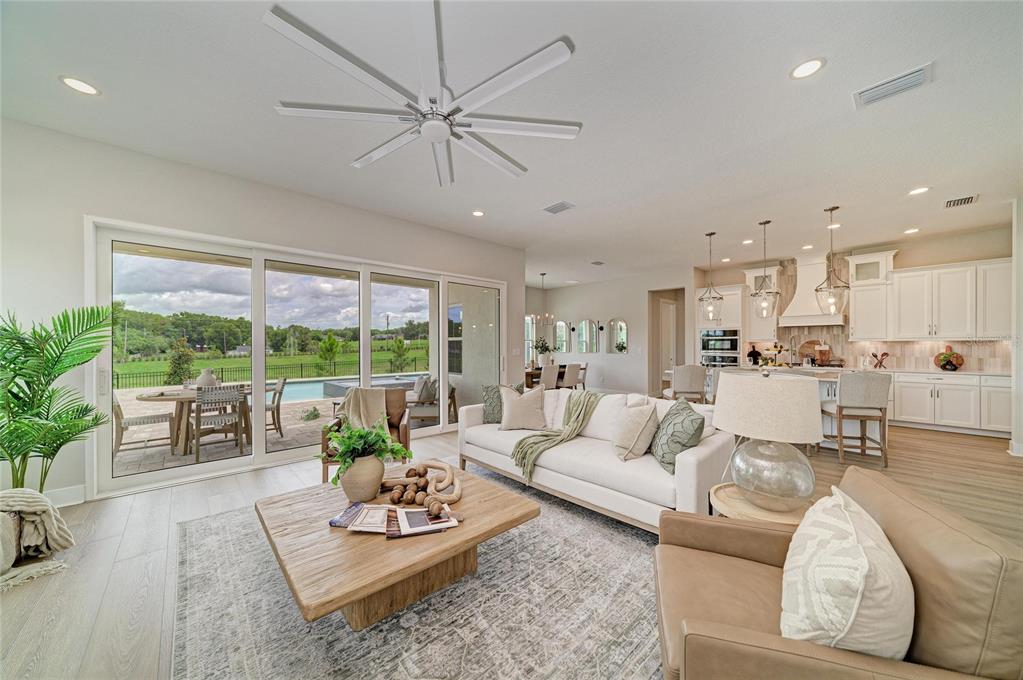 A bright open-concept living room features a white sofa, wood coffee table, and sliding glass doors — 1132 BUCK CREEK COURT, BRANDON, FL