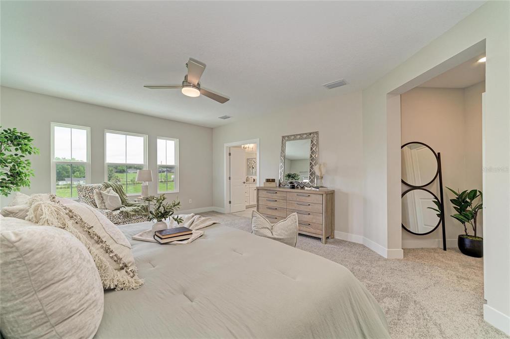 A bedroom features a bed, a dresser with a mirror, and a doorway to a bathroom — 1132 BUCK CREEK COURT, BRANDON, FL