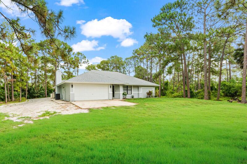 A single-story house with a white garage and gray roof sits on a grassy lot — 12689 N 68th St Street N, FL 33412, FL