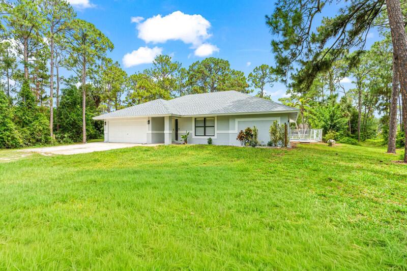 A single-story house with a white garage and gray exterior sits on a grassy lot — 12689 N 68th St Street N, FL 33412, FL