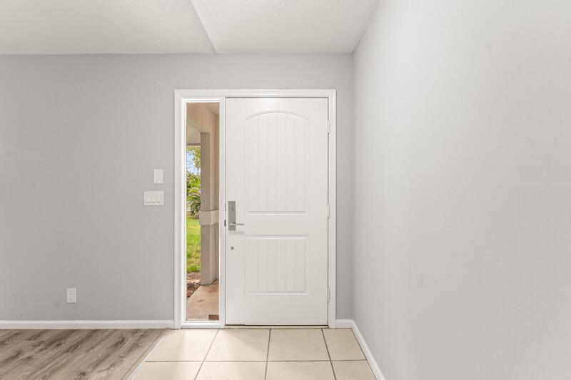 An entryway features a white front door with a side window, tile flooring, and gray walls — 12689 N 68th St Street N, FL 33412, FL