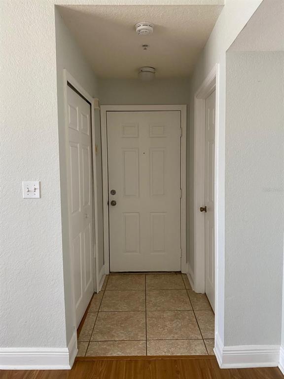A tiled entryway features a white front door flanked by two interior closet doors — 2336 MID TOWN TERRACE UNIT 932, ORLANDO, FL