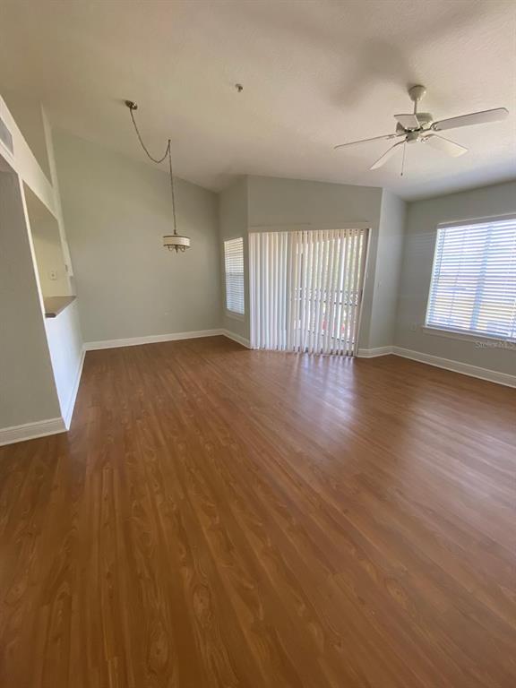 An empty living room features wood-look flooring, a ceiling fan, and sliding glass patio doors — 2336 MID TOWN TERRACE UNIT 932, ORLANDO, FL