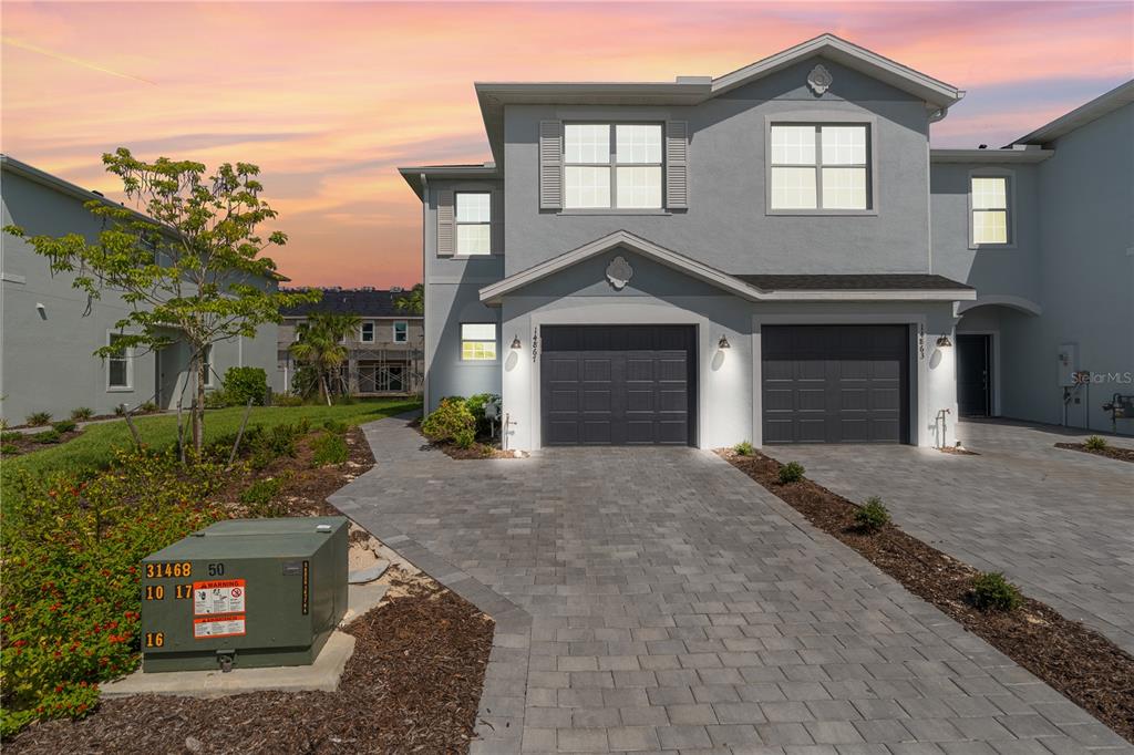 A two-story gray townhouse features a two-car garage and a paved driveway at sunset — 14867 WHITE PEARL ROAD, PUNTA GORDA, FL
