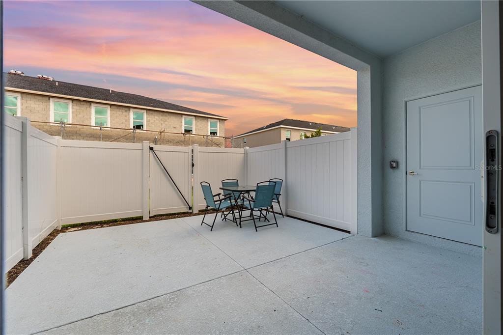 A concrete patio features a small dining set enclosed by a white vinyl privacy fence — 14867 WHITE PEARL ROAD, PUNTA GORDA, FL