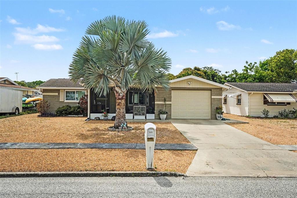 A single-story house with a palm tree, gravel yard, and attached garage — 5828 1ST AVENUE, NEW PORT RICHEY, FL