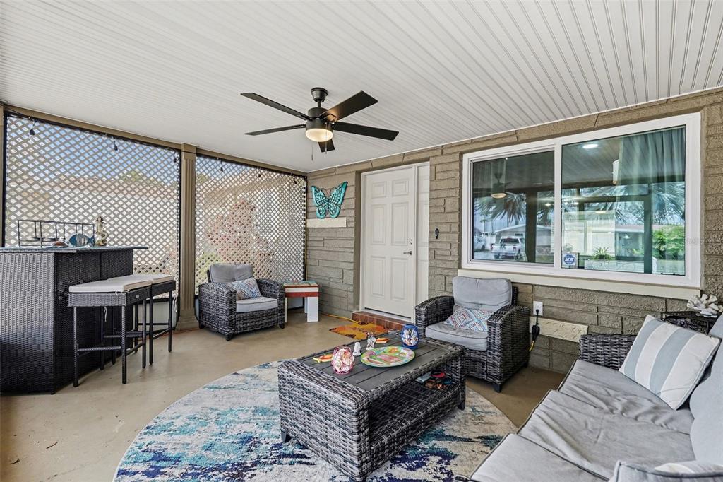 A covered patio features wicker furniture, a ceiling fan, and a lattice privacy screen — 5828 1ST AVENUE, NEW PORT RICHEY, FL