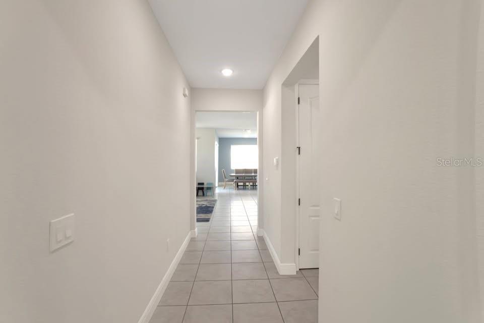 A tiled hallway leads from a neutral-toned entryway toward an open-concept living and dining area — 2587 SUMMER STAR WAY, LEESBURG, FL