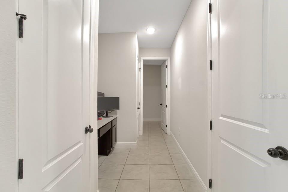 A hallway with tile flooring leads to a small built-in desk area and another room — 2587 SUMMER STAR WAY, LEESBURG, FL