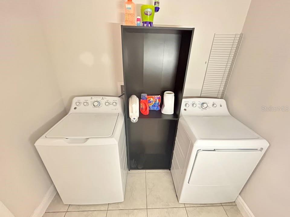 A laundry room features a top-load washer, a dryer, and a central black storage unit — 2587 SUMMER STAR WAY, LEESBURG, FL