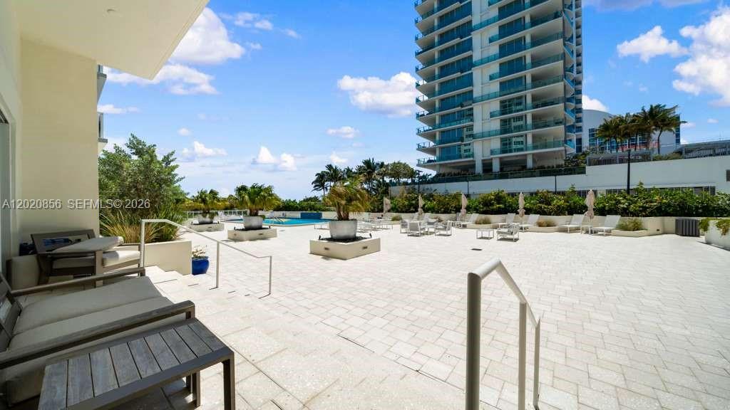 A paved outdoor terrace features lounge seating, potted plants, and a view of a pool — 6917 Collins Ave # 107, Miami Beach FL 33141, MIAMI BEACH, FL