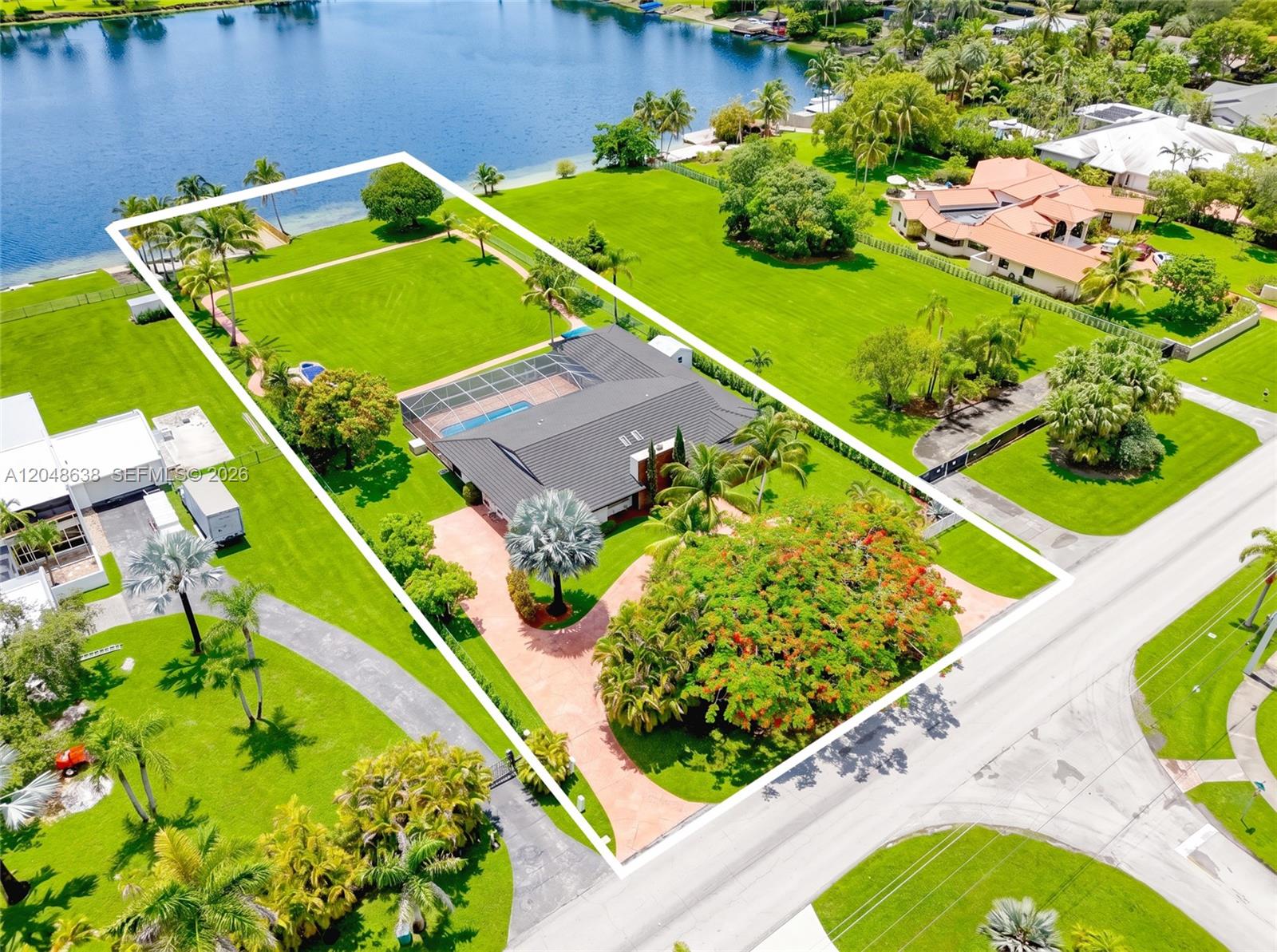 An aerial view shows a house with a pool and large yard beside a lake — 14121 SW 97th Ave, Miami FL 33176, MIAMI, FL