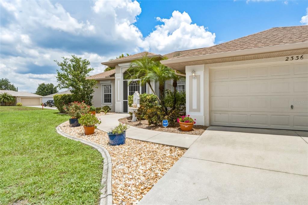 A single-story house exterior features a concrete driveway, a landscaped walkway, and a screened entryway — 2336 BRIARWOOD STREET, PUNTA GORDA, FL