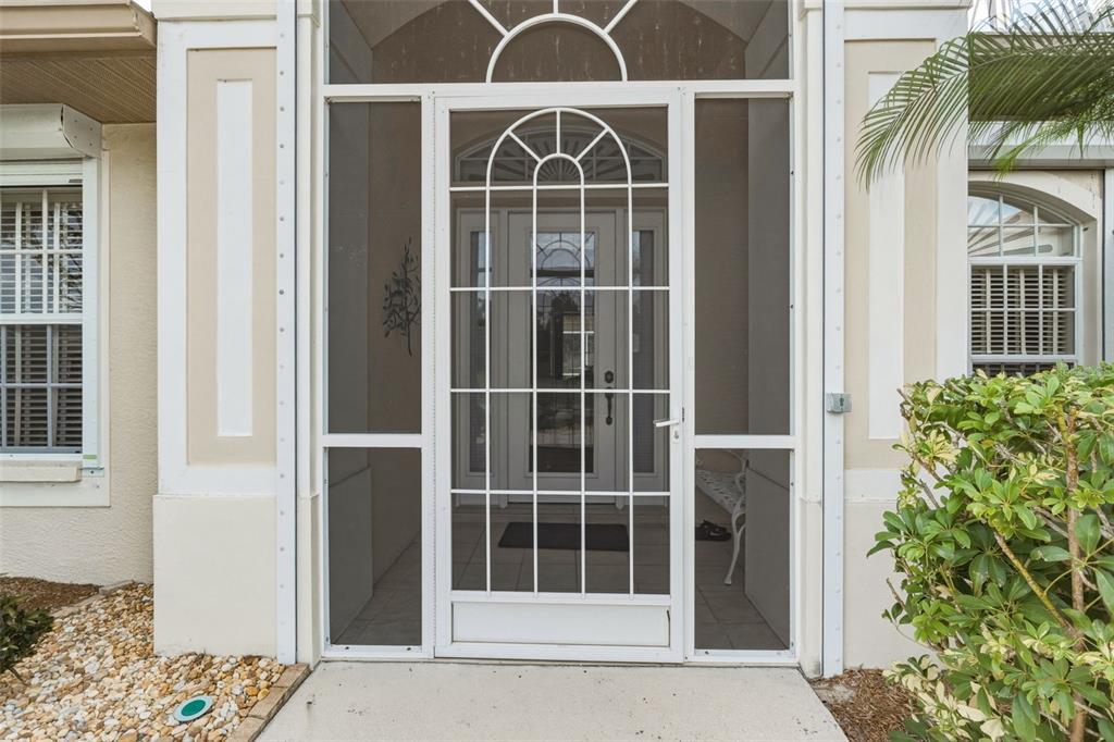 A white screen door with a decorative arch sits at the entrance of a house — 2336 BRIARWOOD STREET, PUNTA GORDA, FL