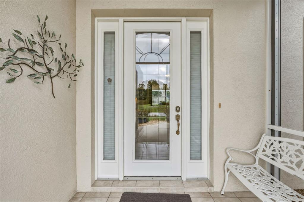 A white front door with glass panels and sidelights sits on a tiled porch — 2336 BRIARWOOD STREET, PUNTA GORDA, FL