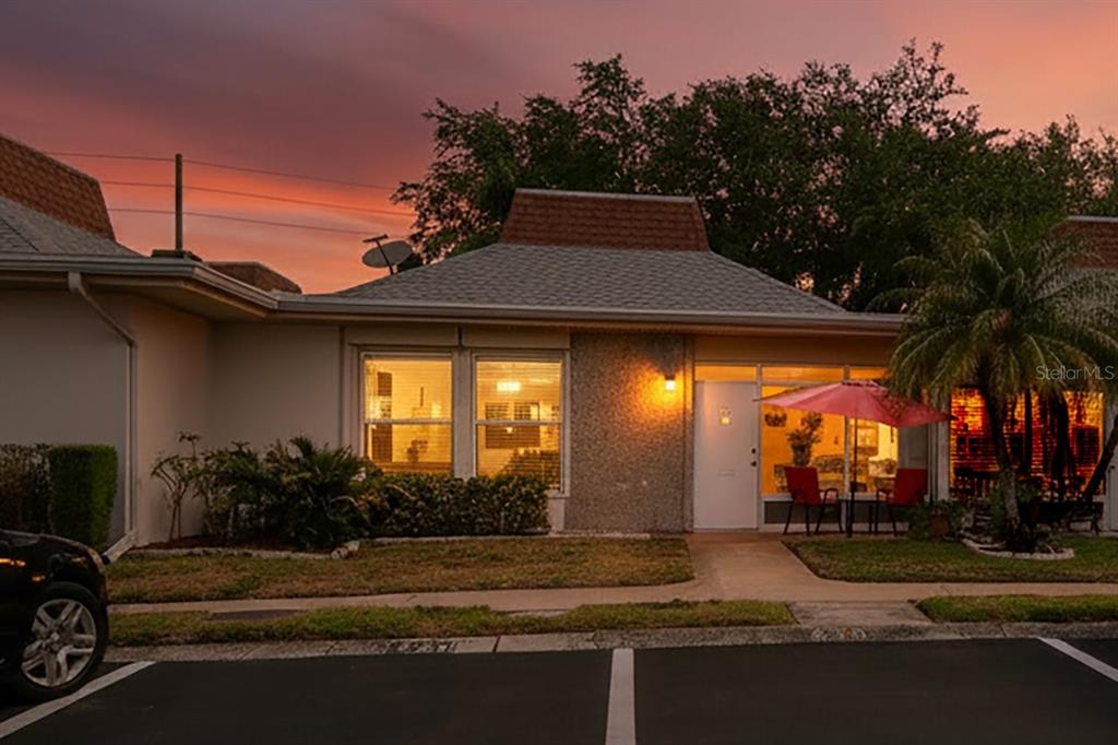 A one-story residential building exterior at sunset with a paved parking area in the foreground — 4363 TAHITIAN GARDENS CIRCLE UNIT B, HOLIDAY, FL