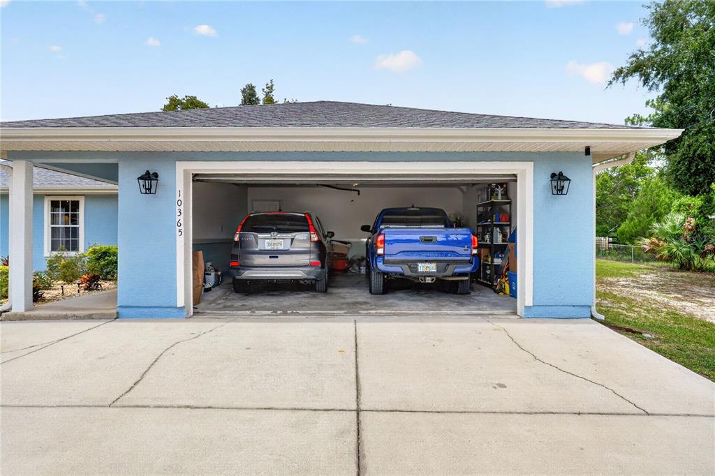 A light blue single-story house features a two-car garage and a concrete driveway — 10365 SE 148TH STREET, SUMMERFIELD, FL