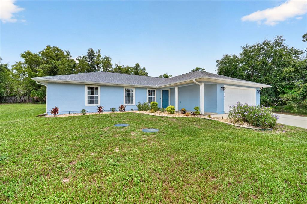 A two-car garage with a blue exterior and a concrete driveway in front — 10365 SE 148TH STREET, SUMMERFIELD, FL