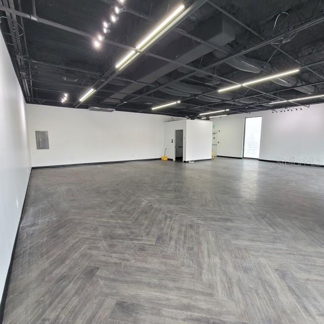 An open commercial space features a dark herringbone floor and an exposed black ceiling — 6124 CENTRAL AVENUE, ST PETERSBURG, FL