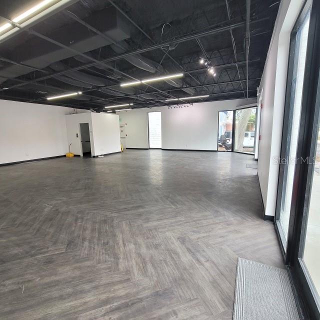 An empty commercial space features dark herringbone flooring, white walls, and an exposed black ceiling — 6124 CENTRAL AVENUE, ST PETERSBURG, FL