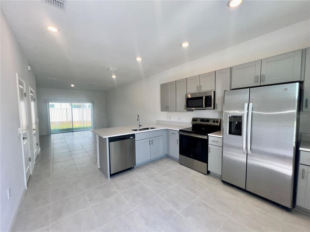 A kitchen with light gray cabinets, stainless steel appliances, and tile flooring — 3200 SKYLINE LOOP, KISSIMMEE, FL