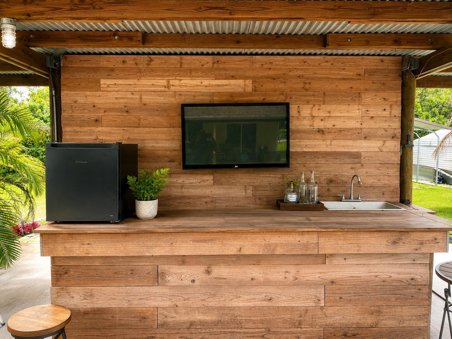 An outdoor bar area features a wooden counter, a sink, a mini-fridge, and a wall-mounted television — 18633 N 92nd Ln Lane N, FL 33470, FL
