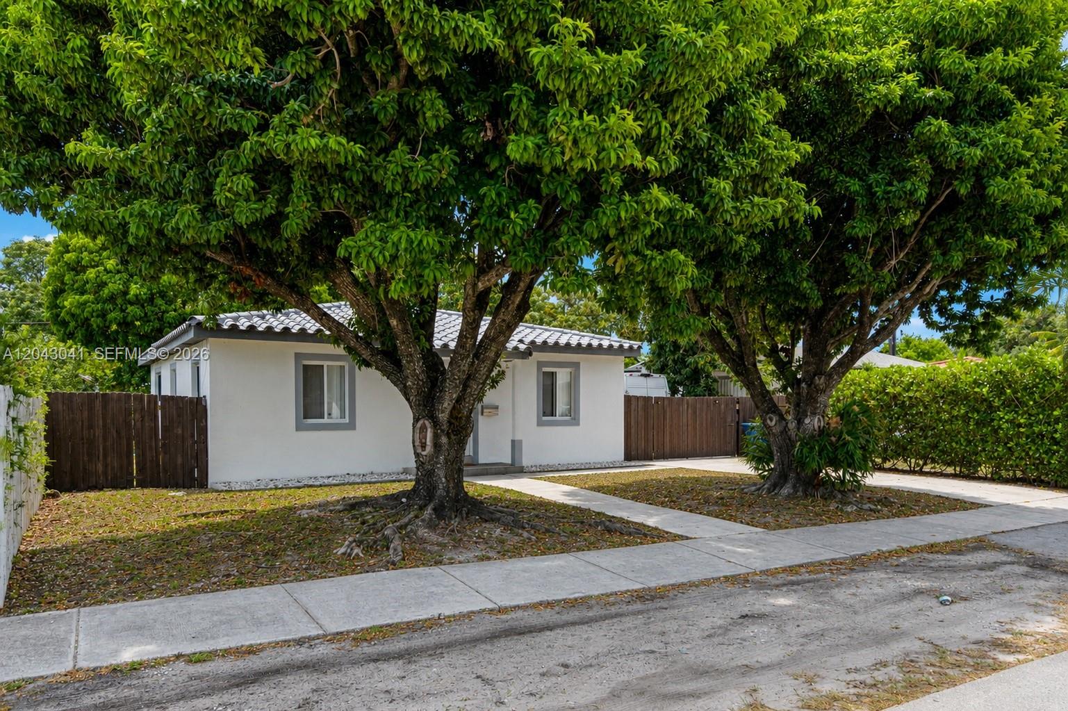 A white single-story house with a tiled roof sits behind two large trees — 270 NW 51st Ave, Miami FL 33126, MIAMI, FL